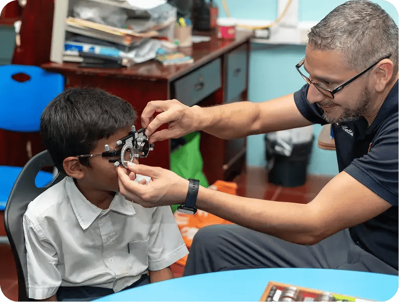 Optometrista realizando examen de la vista a un niño con equipo especializado