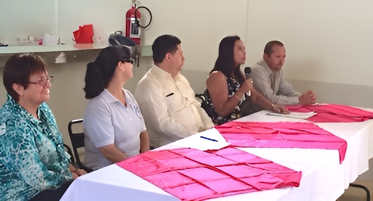 Personas sentadas en mesa durante actividad comunitaria con manteles rosados
