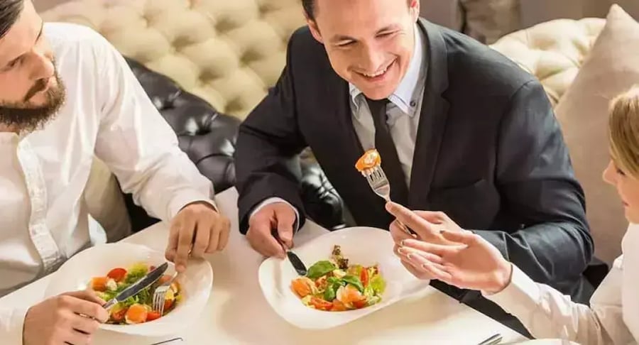 A group of people sharing a healthy salad at a working lunch.
