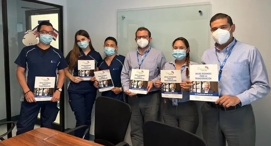 Grupo de colaboradores del hospital posando con documentos en una sala de reuniones.
