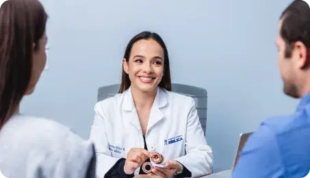 Una médica especialista de Clínica Bíblica atiende en su consultorio a una pareja de pacientes.