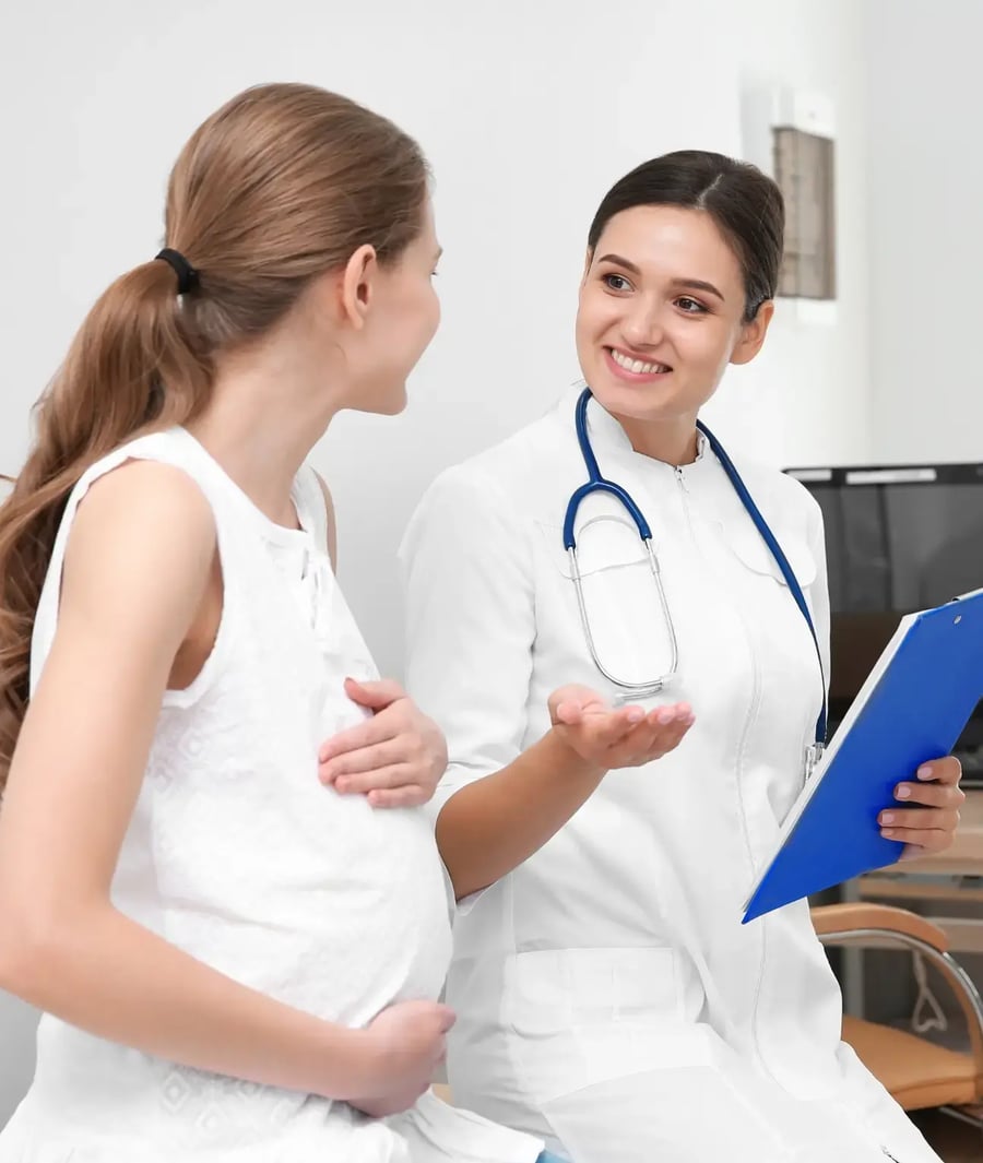 Doctor at Clínica Bíblica attending prenatal consultation with pregnant woman.