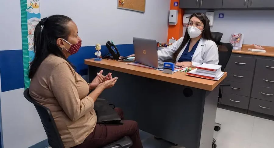 Paciente conversa con una doctora en consultorio médico durante una cita de evaluación.