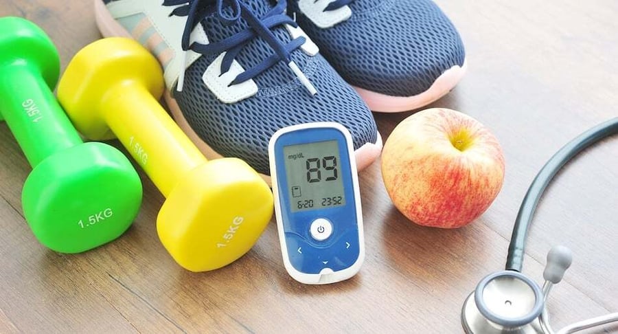 Diabetes monitoring supplies: glucometer, weights, tennis shoes, apple and stethoscope