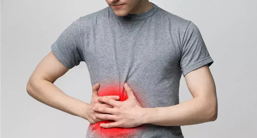 Man with severe abdominal pain holding stomach with reddened area