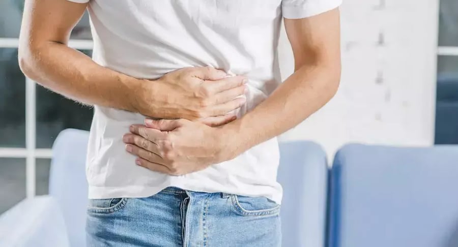 Man with abdominal pain holding lower abdomen with hands