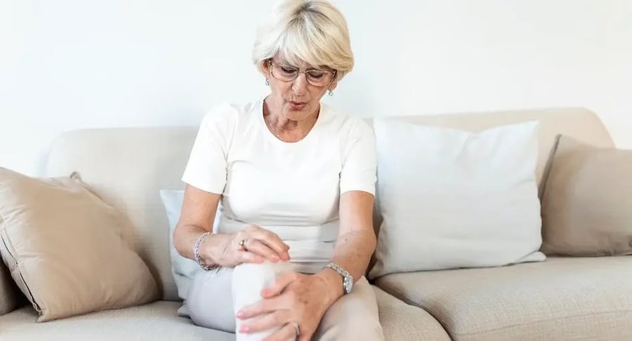Elderly woman sitting on a couch with knee pain