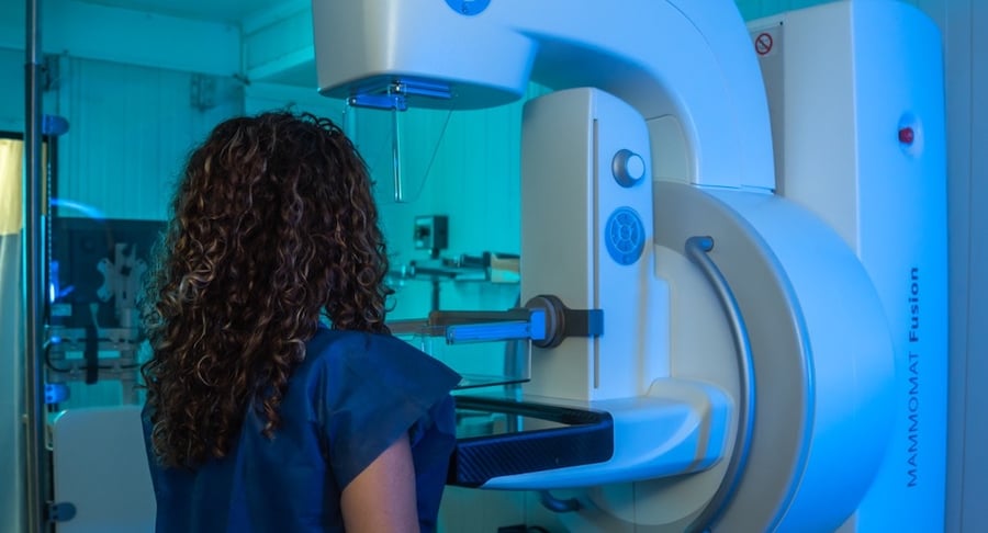 Una mujer de espaldas recibiendo un estudio de mamografía con el moderno equipo digital MAMMOMAT Fusion en una unidad móvil.