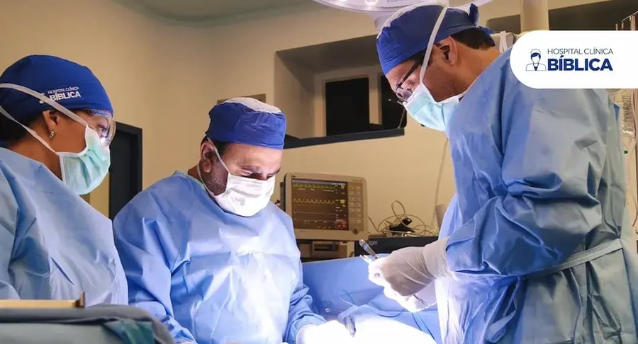 Equipo médico realizando un procedimiento quirúrgico en un quirófano con iluminación y monitores.