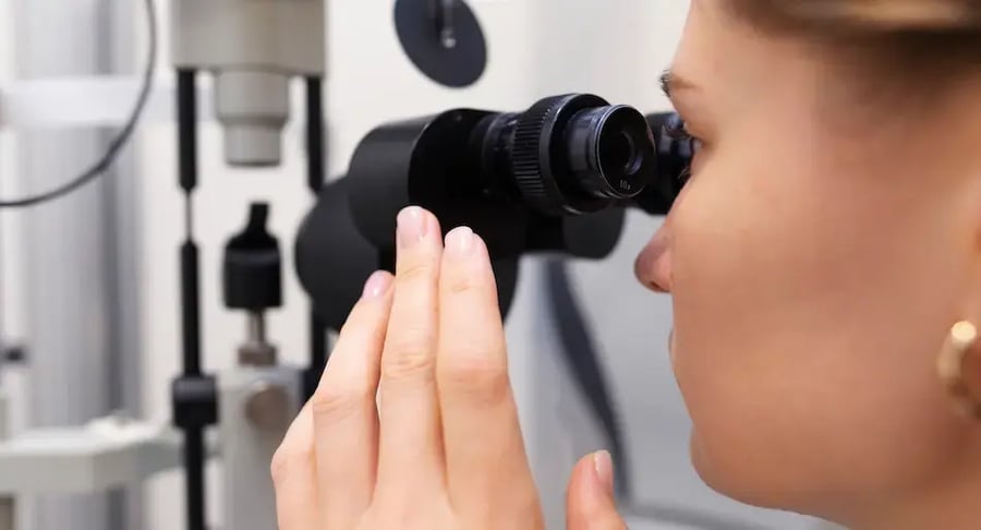 Persona realizando un examen ocular con un equipo de lámpara de hendidura en una consulta de oftalmología.