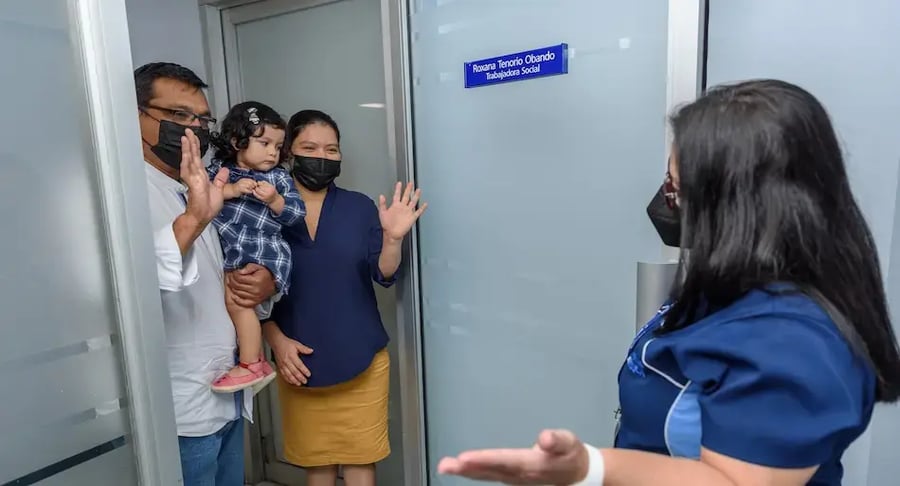 Familia saludando a una trabajadora social en la entrada de una oficina del hospital.
