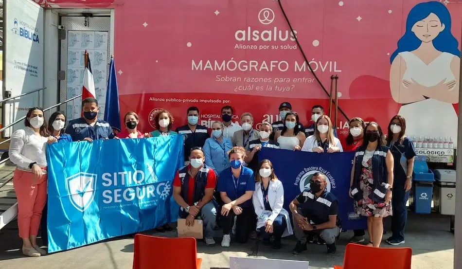 Grupo de profesionales posando frente al mamógrafo móvil de Alsalus durante una actividad de salud.