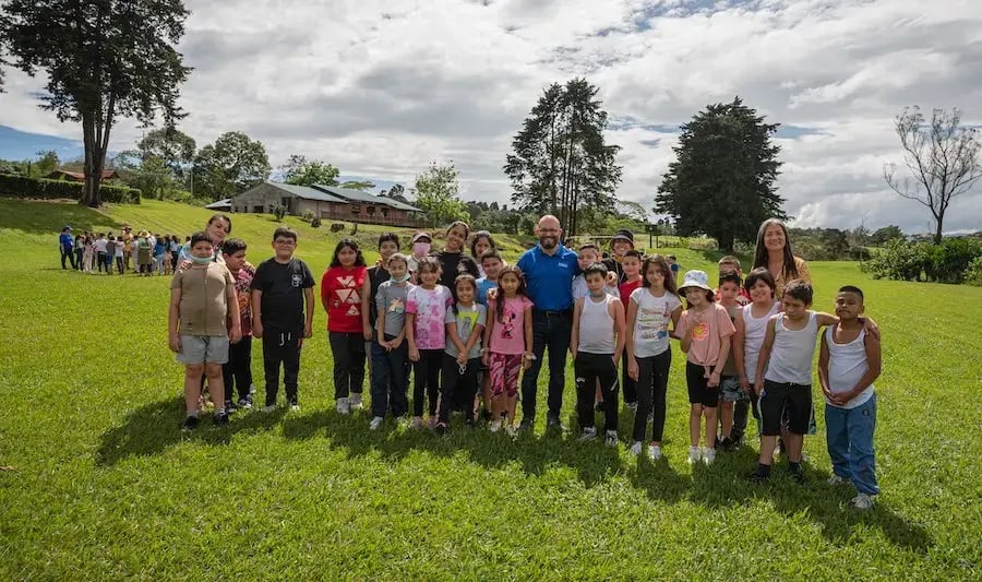 Grupo de niños y adultos posando juntos en un amplio campo de césped.