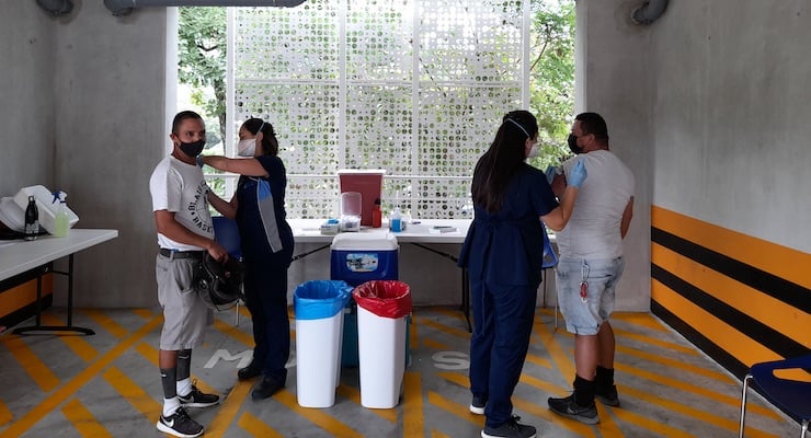 Personal de enfermería del Programa de Acción Social atiende a ciudadanos en el puesto de vacunación instalado en la torre de parqueo de Santa Ana.