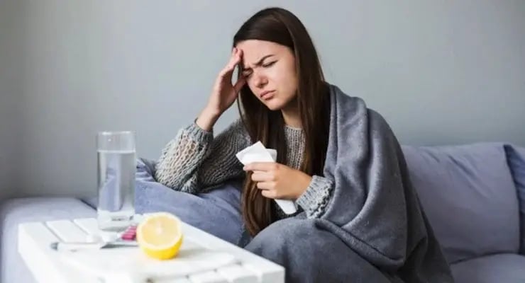 Sick woman at home with fever and headache covered with blanket
