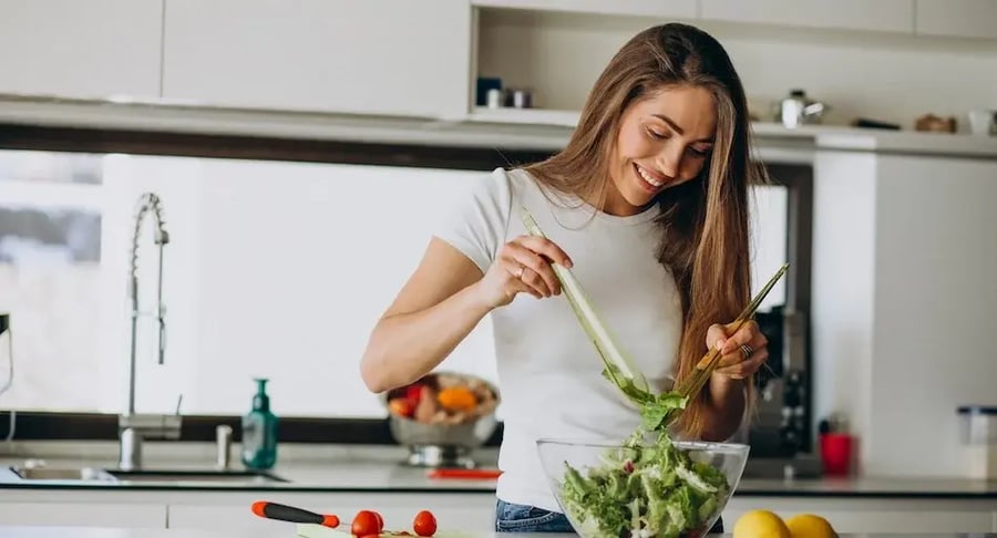 Young woman preparing a healthy salad in the kitchen to prevent diabetes