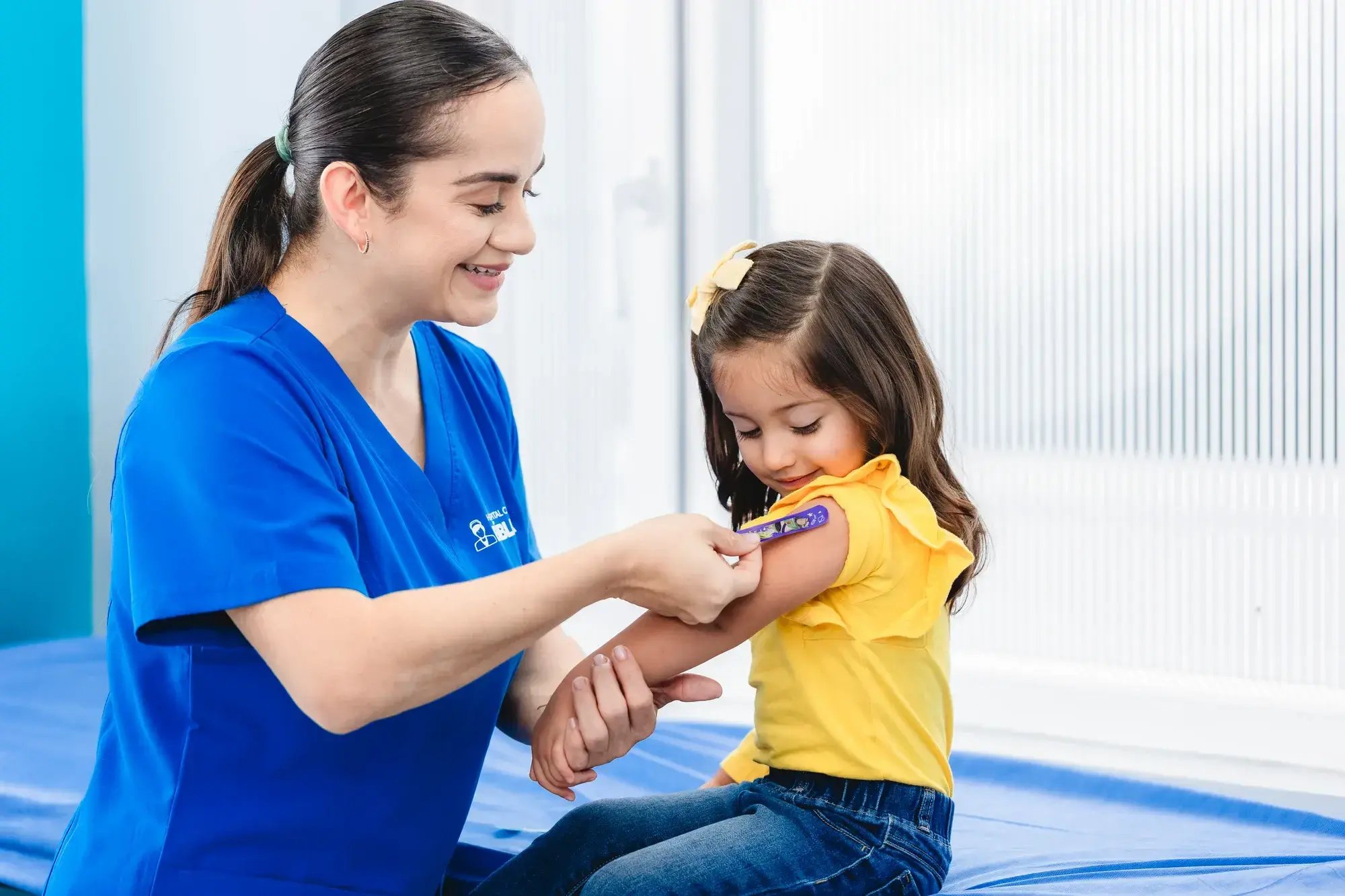 Enfermera coloca curita en el brazo de una niña después de vacuna en Clínica Bíblica Enfermera coloca curita en el brazo de una niña después de vacuna en Clínica Bíblica
