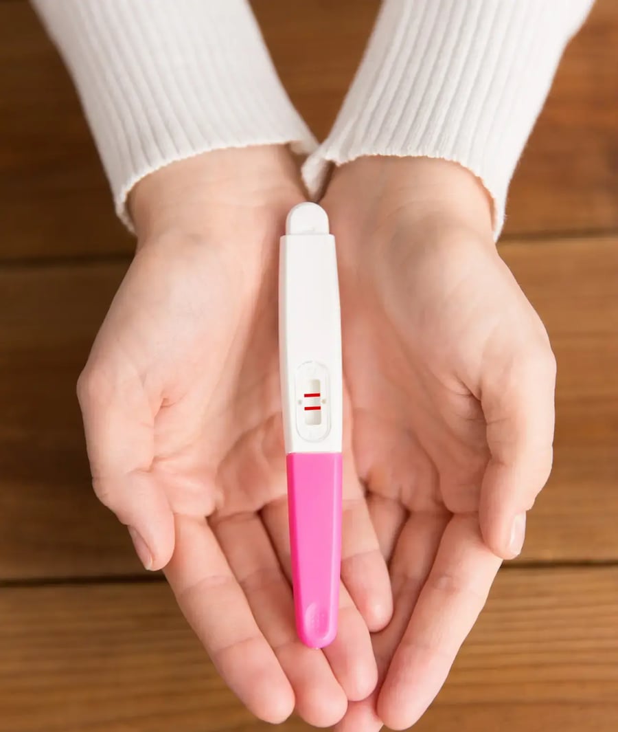 Positive pregnancy test held in a woman's hands