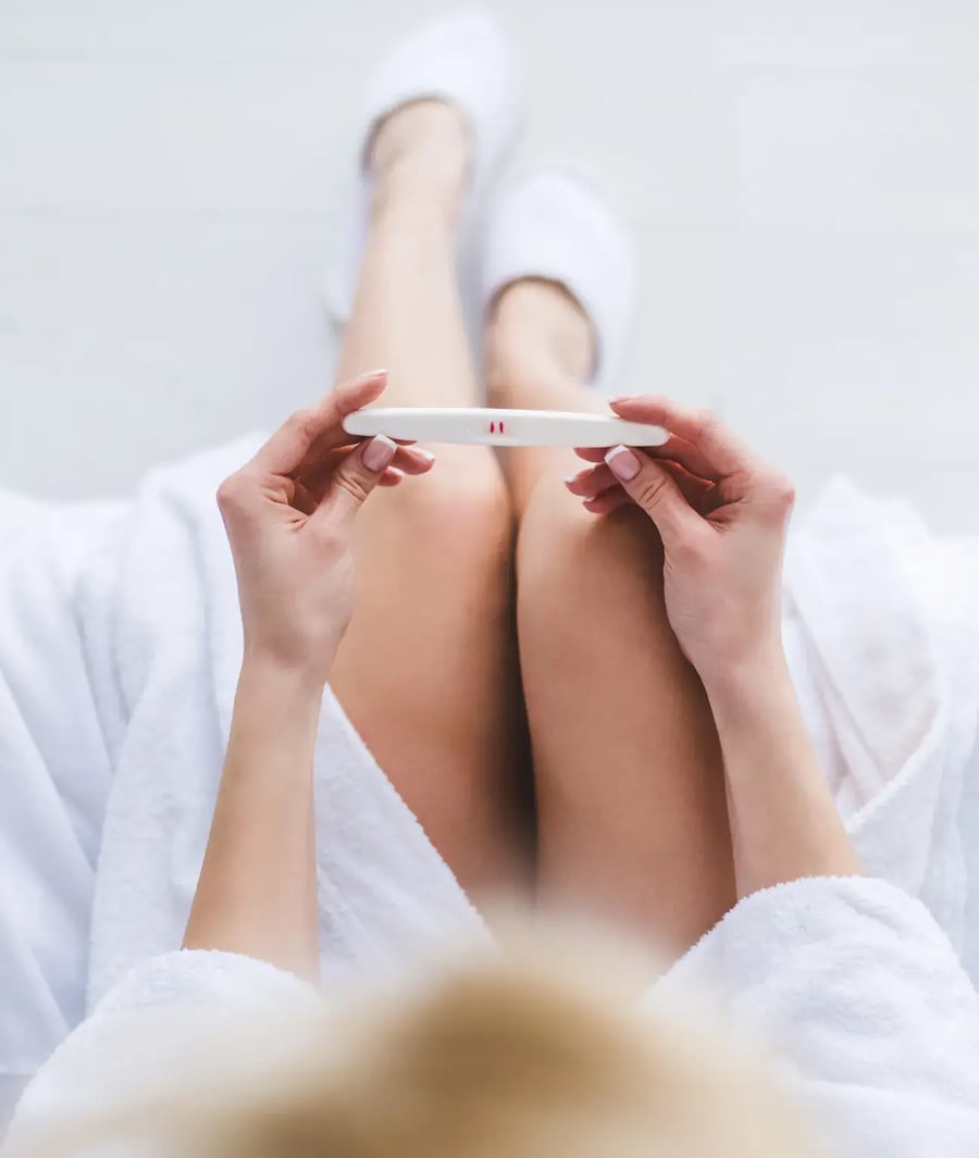 Woman holding positive pregnancy test at Clínica Bíblica.