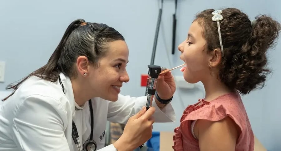 Doctor checking a child's throat during a pediatric medical consultation.