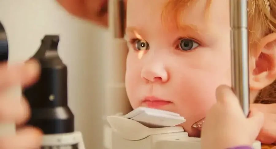 Little girl undergoing ophthalmologic examination with specialized eye equipment