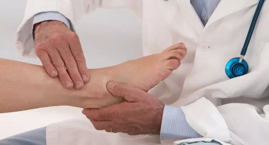 Physician checking a patient's ankle during an orthopedic consultation.