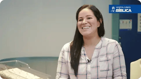 Mujer sonriente compartiendo testimonio en Hospital Clínica Bíblica.