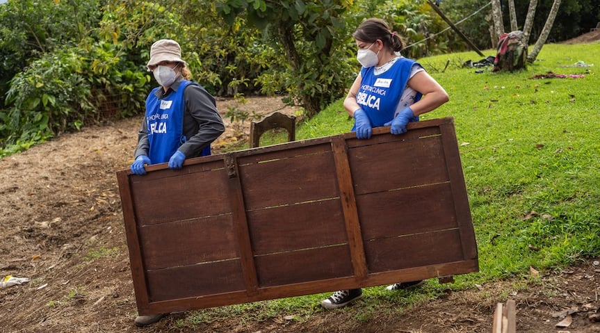 Dos voluntarias del Programa de Acción Social trasladando estructuras de madera para acondicionar el albergue indígena.