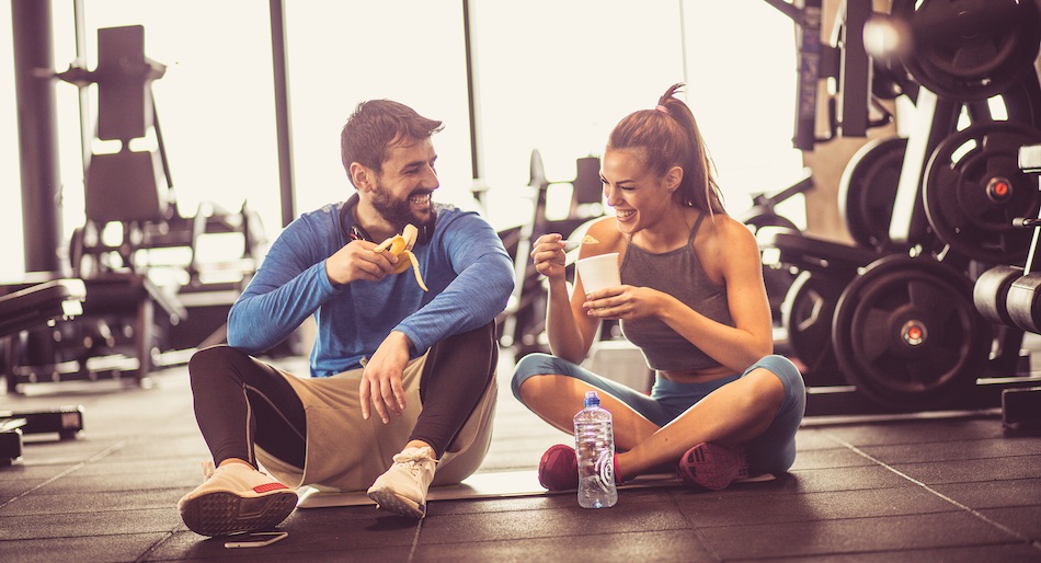 Young couple at the gym eating and drinking after workout.